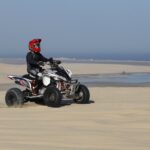 Jazdec na štvorkolke v teréne s ochrannou prilbou a bezpečnostným vybavením.